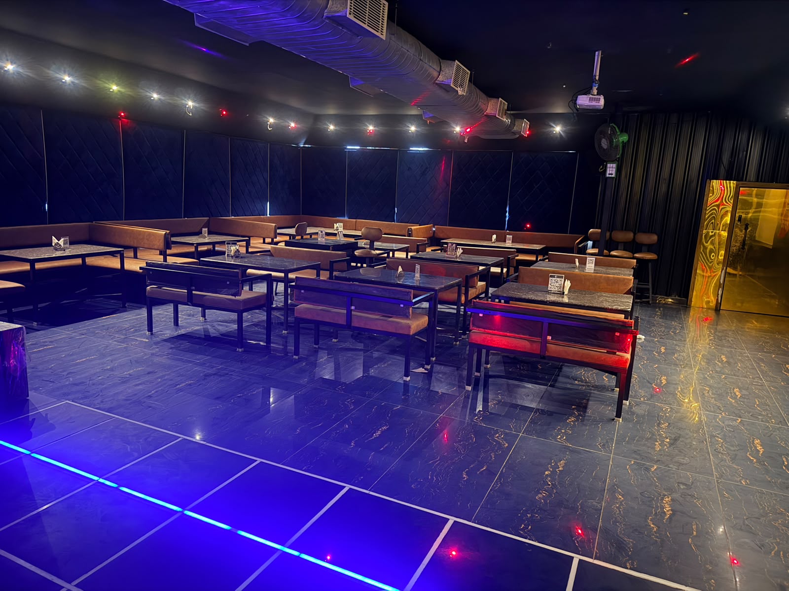 Reserved booth seating and tables lit in blue and red for a group celebration at Gravity