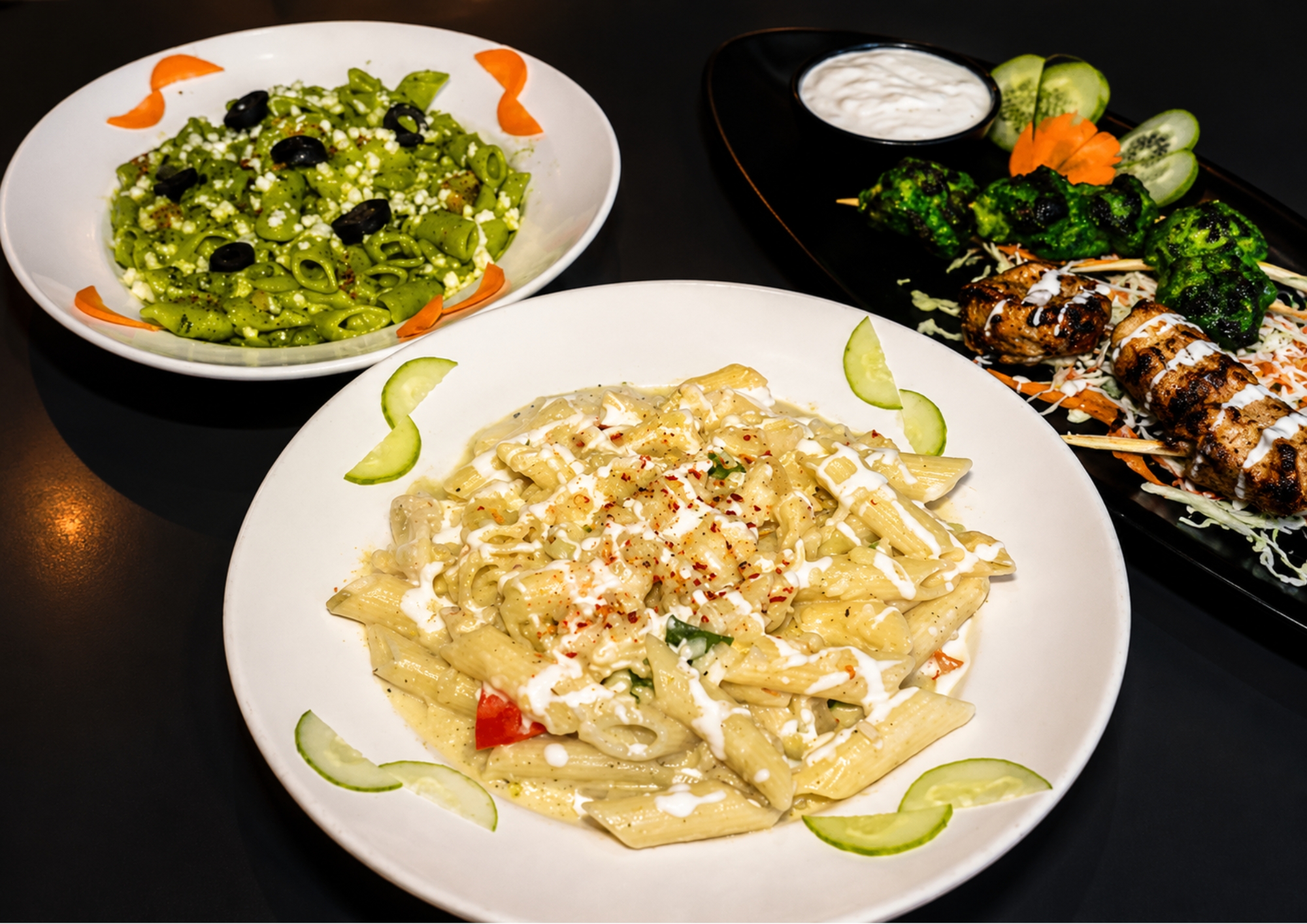 Creamy penne, pesto pasta and grilled skewers spread across a table at Gravity