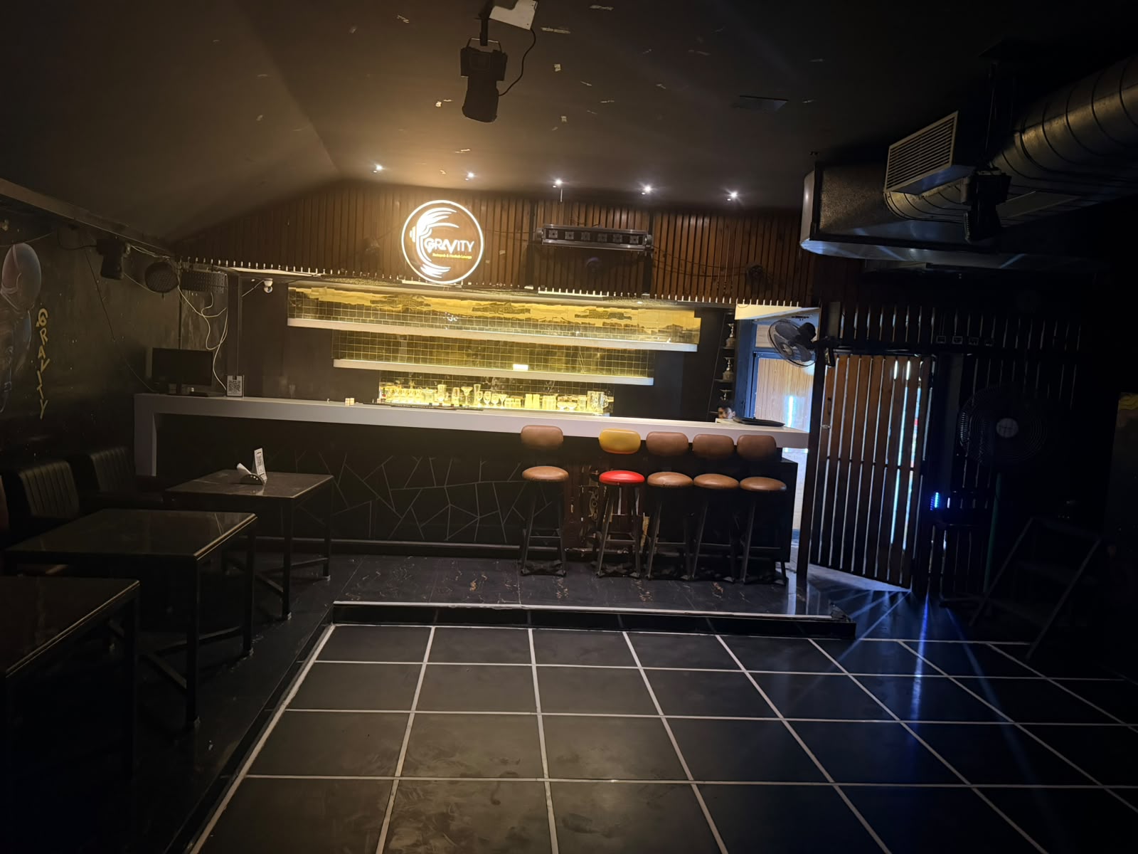Warmly lit counter and high stools under the glowing Gravity sign